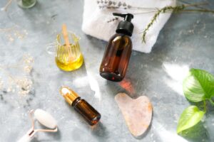 Stylish flat lay showcasing beauty products with oils, jade roller, and leaves for a natural skincare routine.