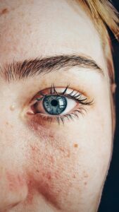 Detailed close-up of a woman's blue eye showcasing natural skin texture and eyebrow.